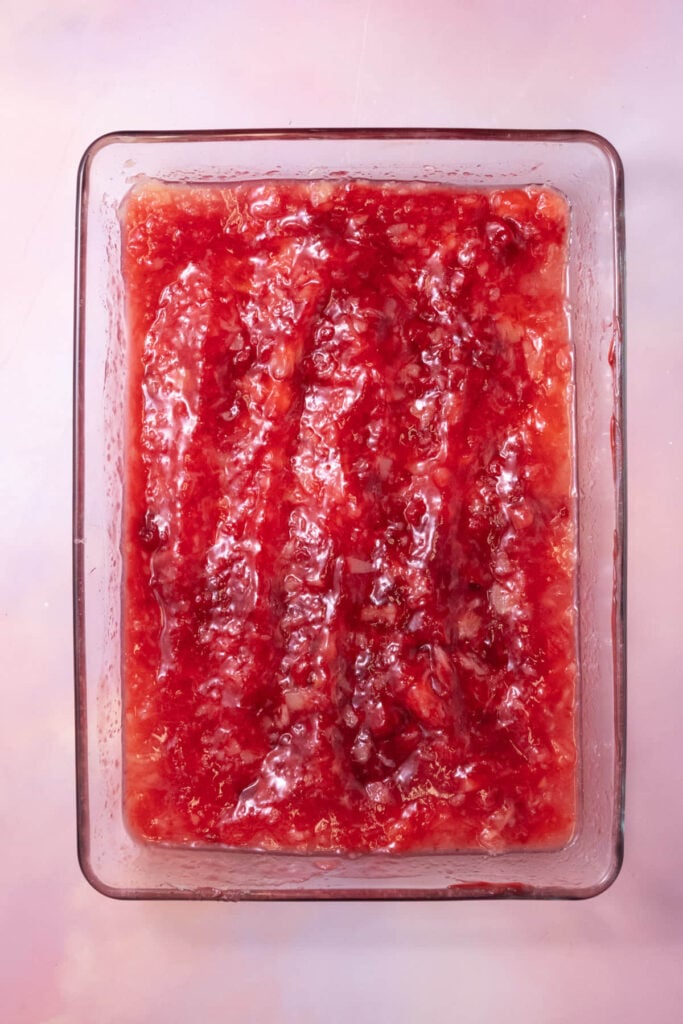 A can of crushed pineapple and a can of cherry pie filling mixed together in a casserole dish.