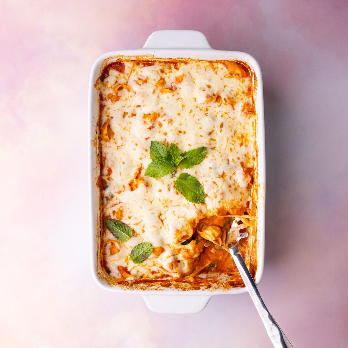 Baked Tortellini Casserole Garnished with Fresh Herbs Cheese tortellini casserole baked with a melted cheese layer on top.