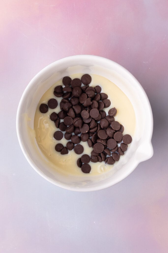 Condensed milk and chocolate chips together in a microwave-safe bowl.