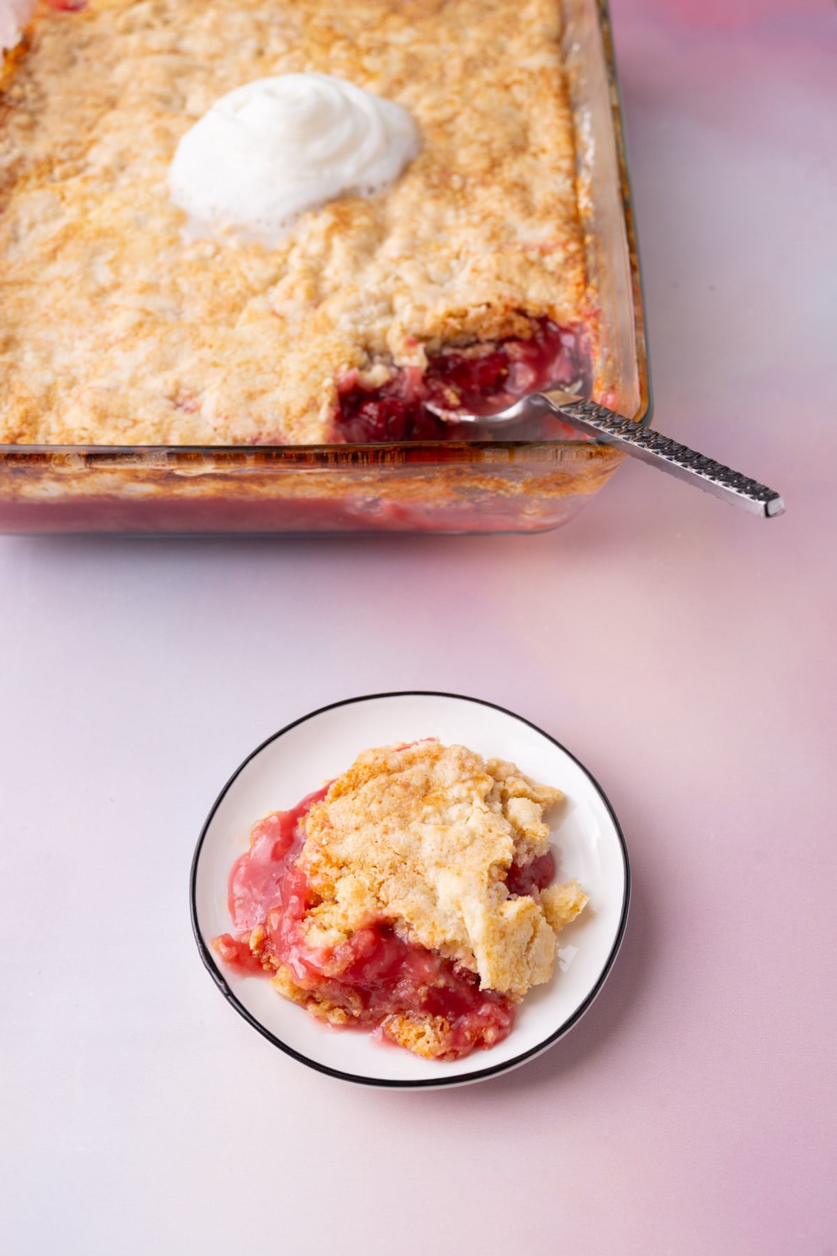 Serving of Pineapple Cherry Dump Cake on a plate with the whole dish in the background.
