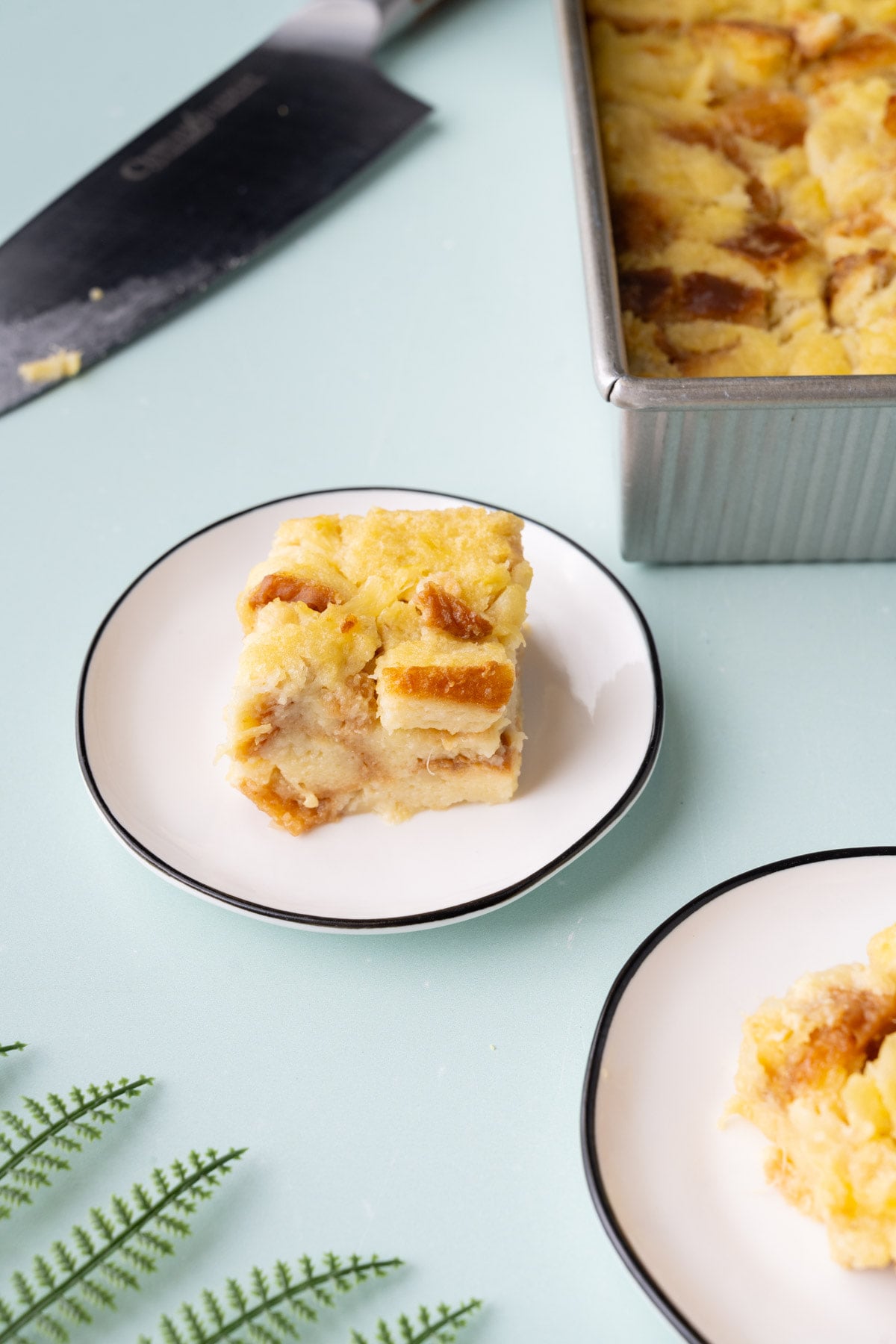 Slice of bread pudding with pineapple on a plate with a blue background.