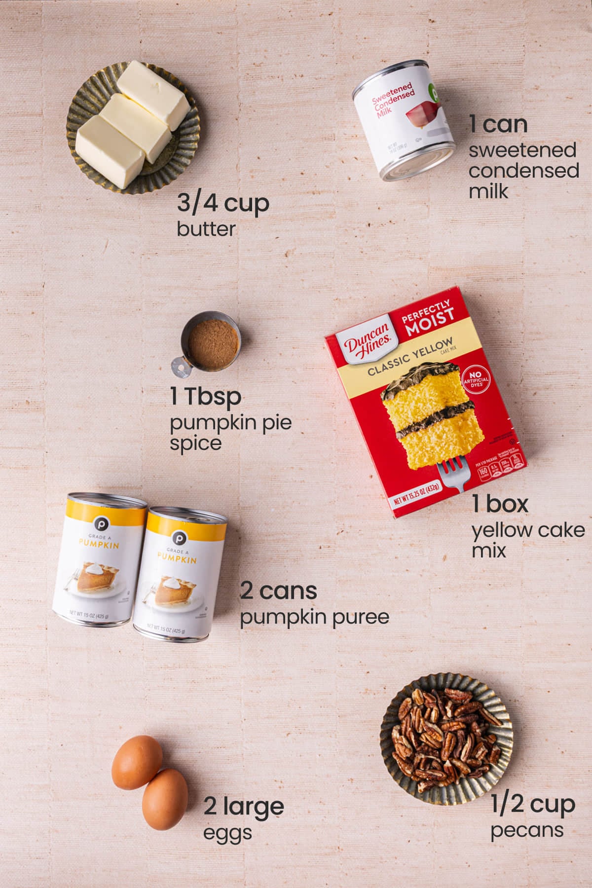 Everything you need to make pumpkin dump cake including butter, sweetened condensed milk, pumpkin pie spice, yellow cake mix, pumpkin puree, pecans (optional), and eggs.