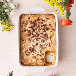 Casserole dish with freshly baked pumpkin dump cake with a slice taken out of the corner.