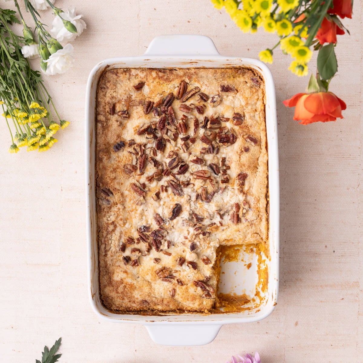 Pumpkin Dump Cake with Slice Taken Out Casserole dish with freshly baked pumpkin dump cake with a slice taken out of the corner.