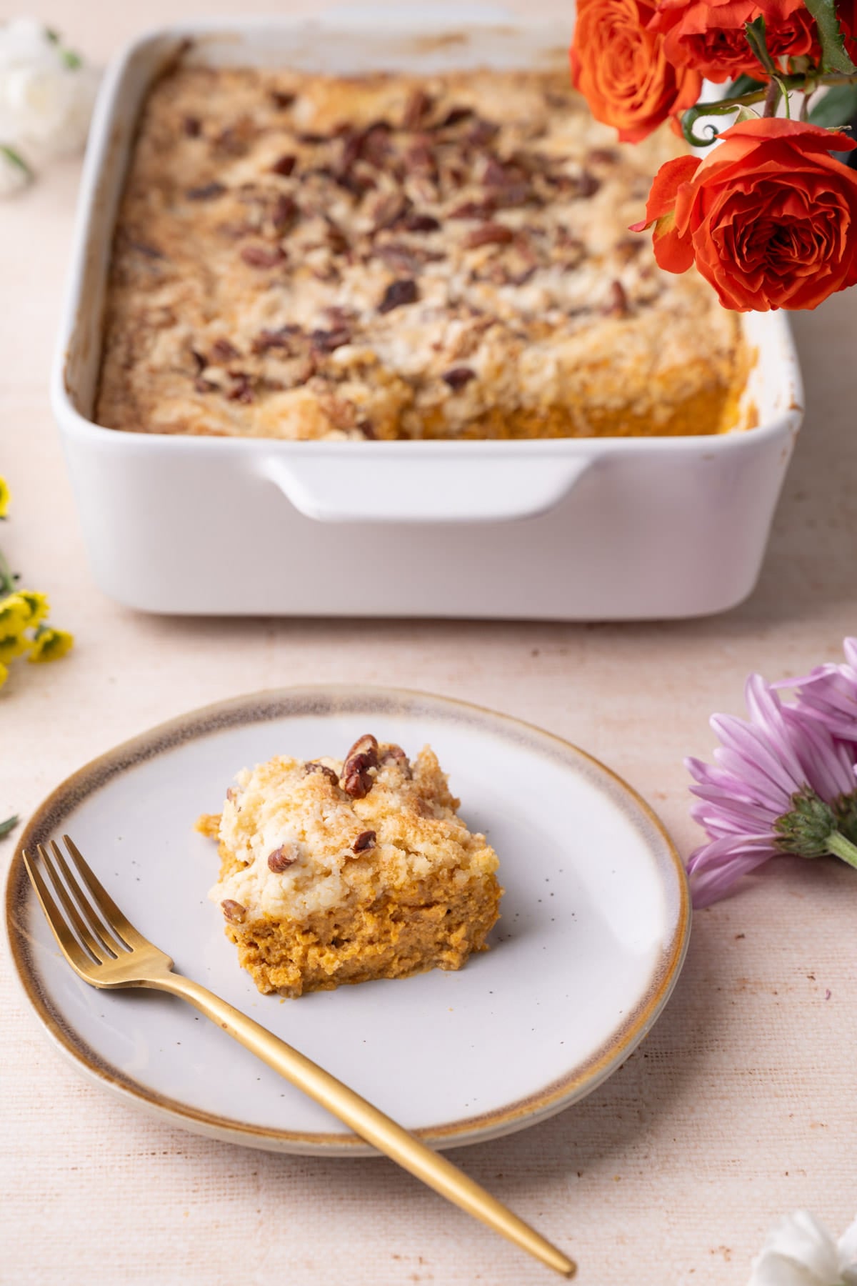 Slice of pumpkin dump cake on a plate showing the distinct layers of pumpkin pie filling and crumbly yellow cake on top.