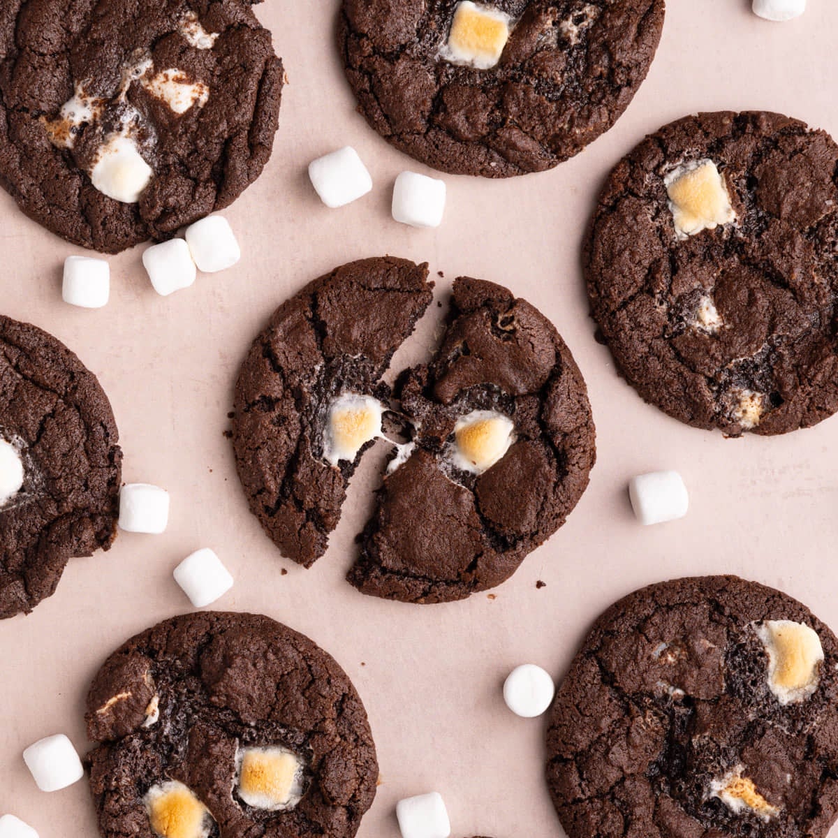 Chocolate marshmallow cookies with the center one broken in half, showing the sticky gooey marshmallows.